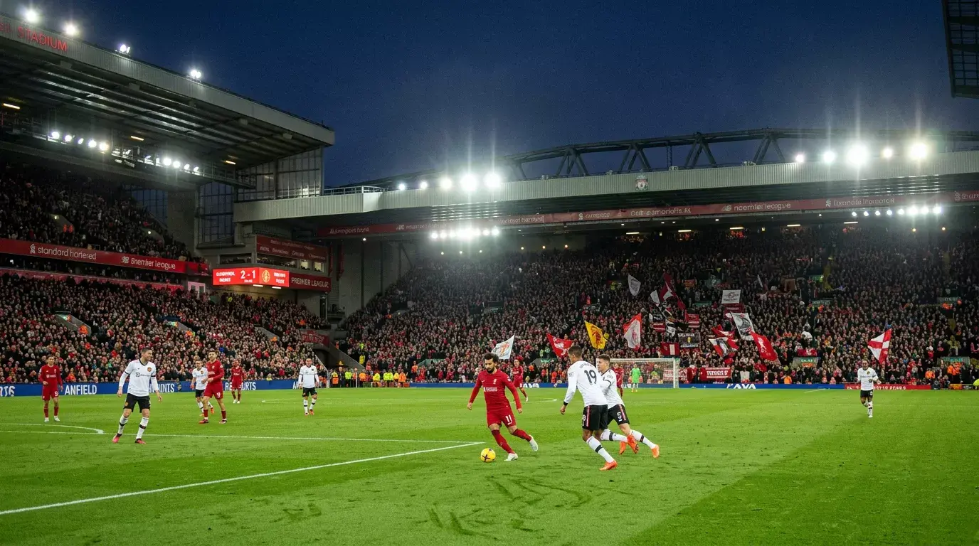 Estadio de fútbol inglés iluminado durante un partido nocturno de la Premier League con marcador electrónico visible